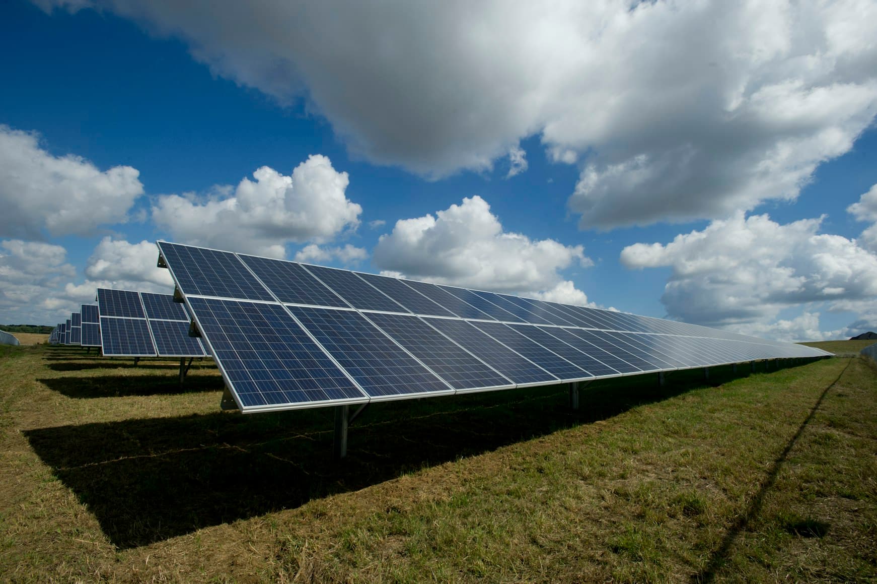 Rows of solar photovoltaic panels under a bright sky.